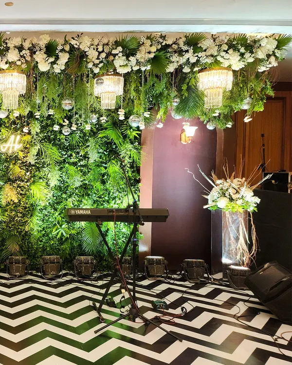 A perfect setup for a live band or DJ at a Sangeet. We created a lush green foliage wall as a backdrop, with a ceiling installation of hanging greenery, chandeliers, and disco balls over a bold chevron dance floor.