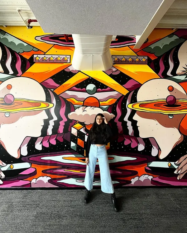 Here I am with the completed customer service-themed mural at the Rippling office. It's incredibly rewarding to see a digital design come to life at this scale.