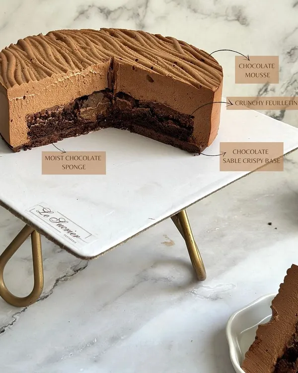 The anatomy of my Chocolate Dream Entremet. It features a chocolate sable base, moist chocolate sponge, a crunchy feuilletine layer, and is topped with a light, airy chocolate mousse.