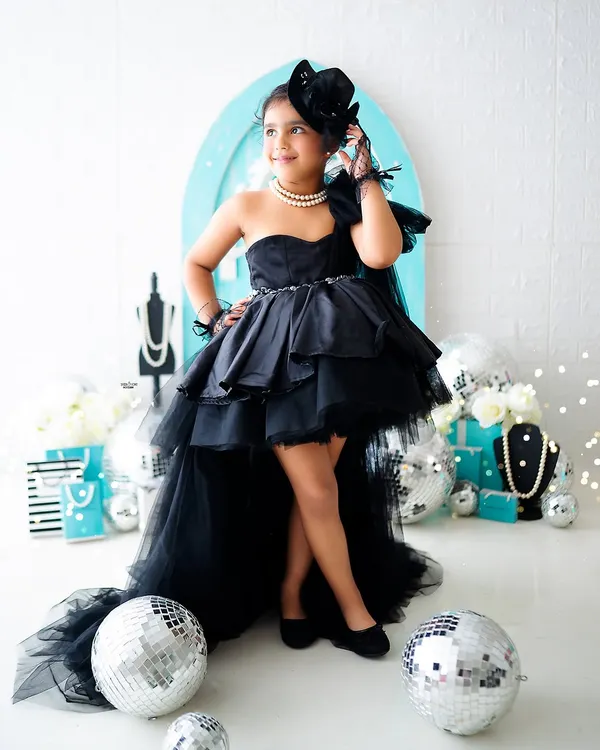 Channeling her inner Audrey Hepburn! This little fashionista is striking a pose in a "Breakfast at Tiffany's" inspired photoshoot. The custom black dress and pearl necklace complete the glamorous look.