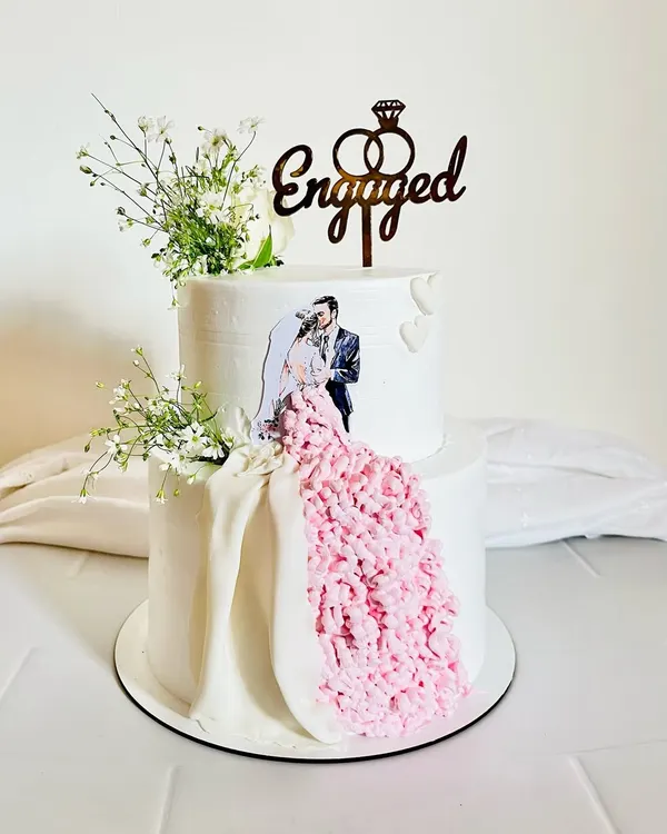 This two-tier engagement cake is all about celebrating love. I incorporated the couple's photo and created a flowing gown effect with delicate pink frosting, all finished with fresh baby's breath. It’s a perfect example of how I can personalize a cake to make your big day even more memorable.