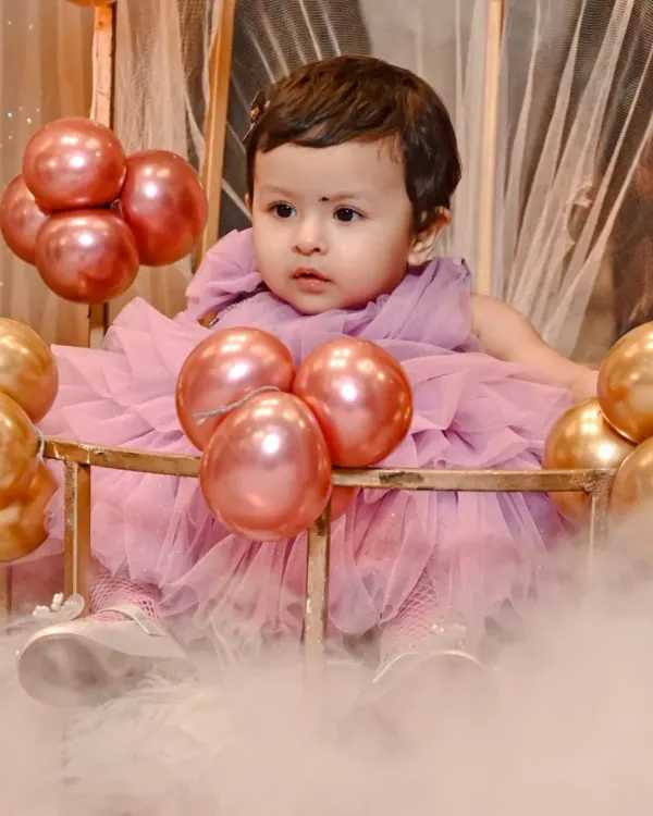 A candid portrait of the birthday girl, Yasmeen, during her first birthday celebration. I aimed to capture her innocent curiosity amidst the beautiful party decor of pink and gold balloons.