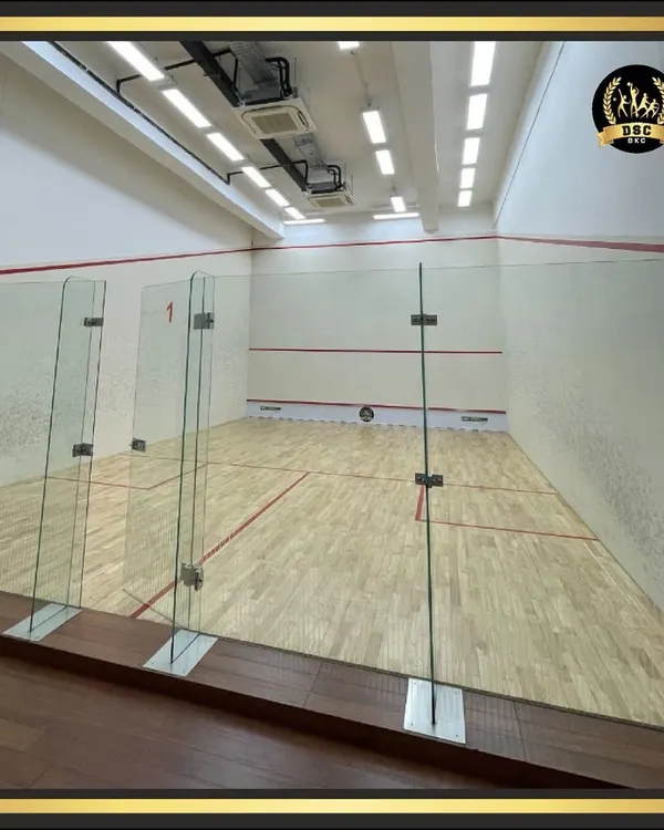 An empty view of our pristine, air-conditioned squash court. The space is well-lit with professional-grade wooden flooring, ready for your next match.