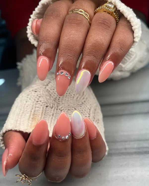 A beautiful peach-colored manicure with glamorous accents. This set features an iridescent chrome accent nail and delicate silver chain details for a touch of bling.