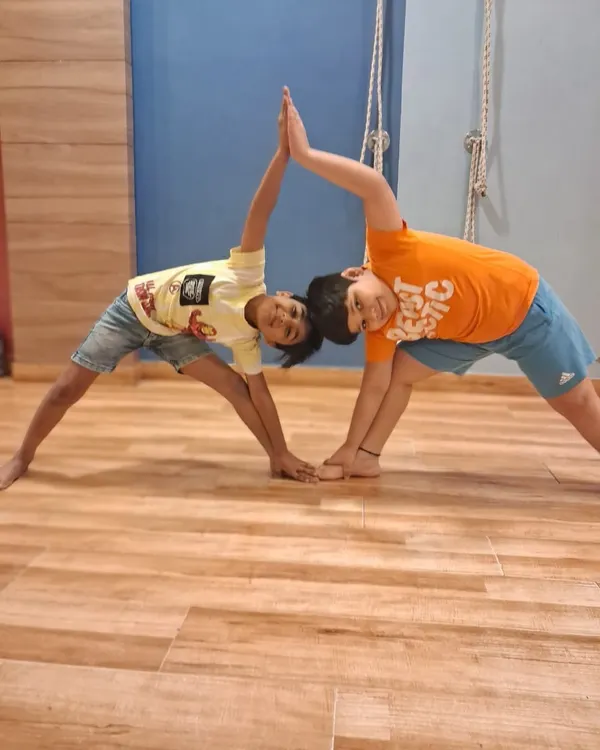 Two boys from our summer camp create a partner triangle pose. Our kids' yoga sessions focus on making fitness collaborative and enjoyable.