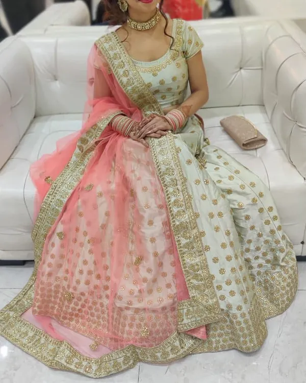 A client seated comfortably in our pista green lehenga with a peach dupatta. The gold butti work on the skirt and the embroidered border make it a graceful choice for any wedding guest.