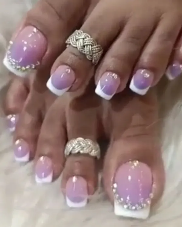 A close-up of our detailed pedicure art, featuring a purple and white ombre with a border of tiny rhinestones on the big toe.
