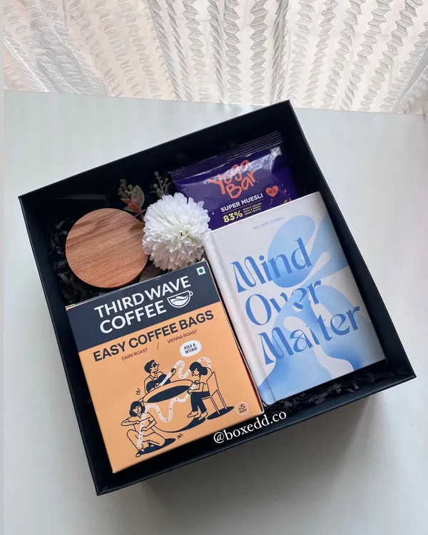 A wellness hamper perfect for International Yoga Day. It includes a "Mind Over Matter" journal, Third Wave coffee bags, and healthy snacks to encourage a moment of pause and reflection.