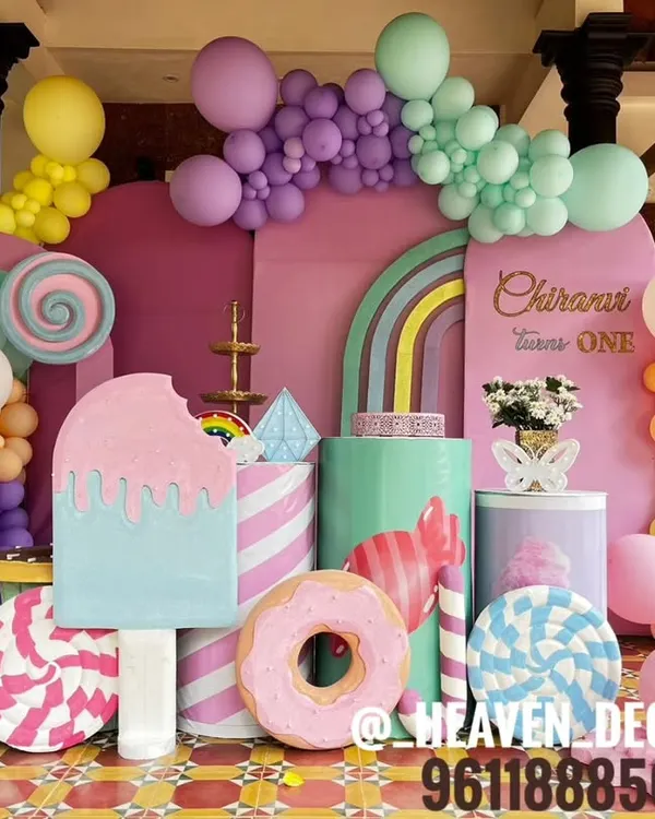 A spectacular Candyland-themed first birthday party, filled with oversized props. The setup includes giant ice cream, donut, and lollipop cutouts, all in a vibrant pastel color palette.