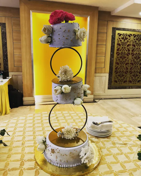 This three-tier floating wedding cake is a true showstopper. We designed this lilac and gold masterpiece to be as magical as the special day itself, complete with fresh flowers and delicate details for an elegant celebration.