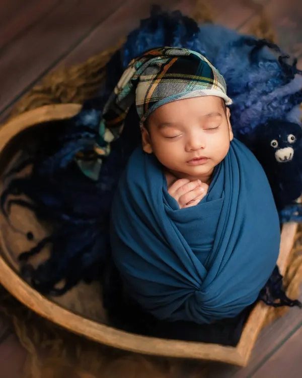 A sweet sleeping baby boy, snugly wrapped in blue and nestled in a heart-shaped bowl. This is a classic example of my posed studio newborn photography.