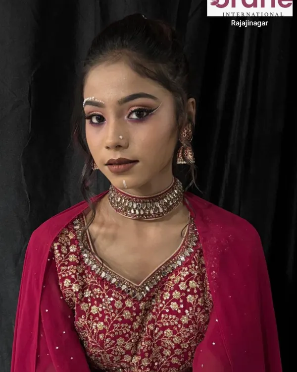 A creative airbrush makeup look featuring decorative pearl bindis and sharp, graphic eyeliner. This demonstrates how airbrush techniques can be used for both a flawless base and artistic details.