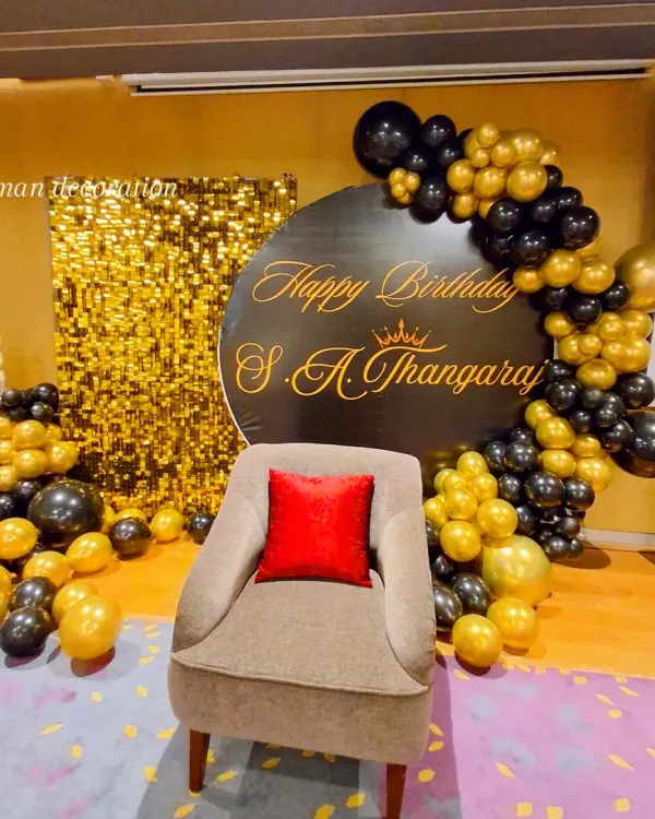 A grand 95th birthday celebration with a classic black and gold theme. The setup includes a gold sequin wall, a personalized circular backdrop, and a balloon arrangement.