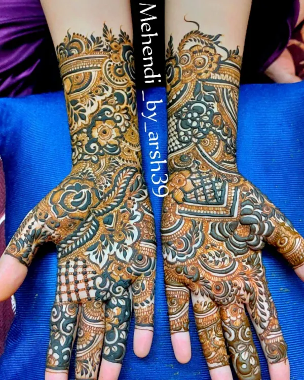 A stunning example of a full-coverage bridal design with fresh, dark henna paste. The contrast highlights the intricate details, including checkerboard fills, delicate vines on the fingers, and bold floral work on the palms.