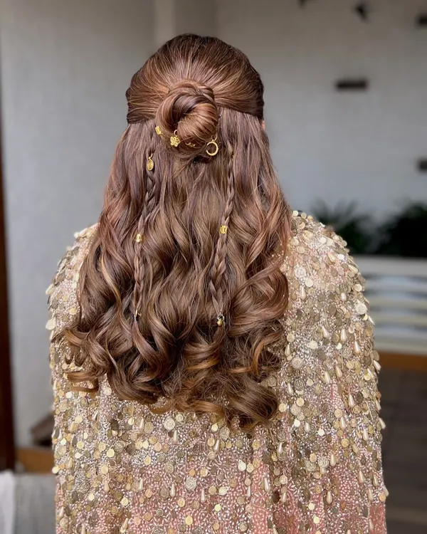 A close-up of the beautiful half-up, half-down hairstyle. We added delicate braids and gold charms to the soft waves for a touch of modern romance.