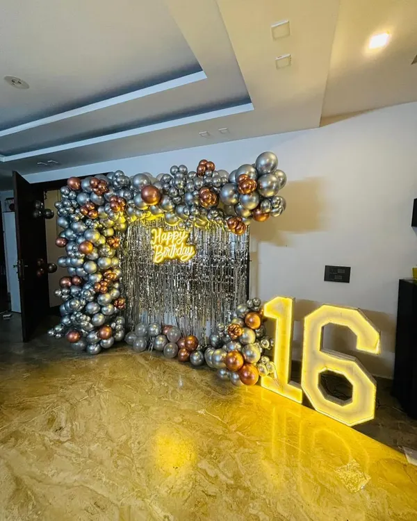 This glam party backdrop features a silver shimmer wall that catches the light beautifully. We framed it with a modern balloon arch in metallic silver and rose gold, complemented by a "Happy Birthday" neon sign and large marquee numbers.