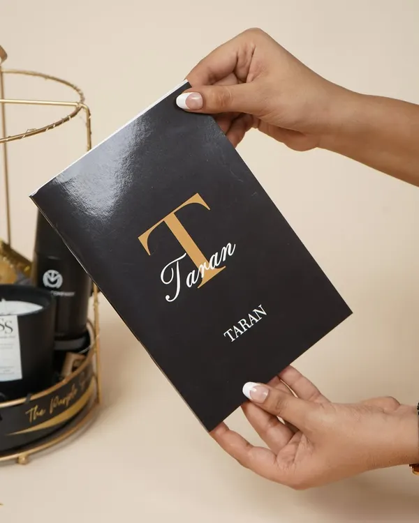 A personalized notebook for "Taran," part of a birthday hamper for him. The elegant monogram adds a sophisticated, custom touch.