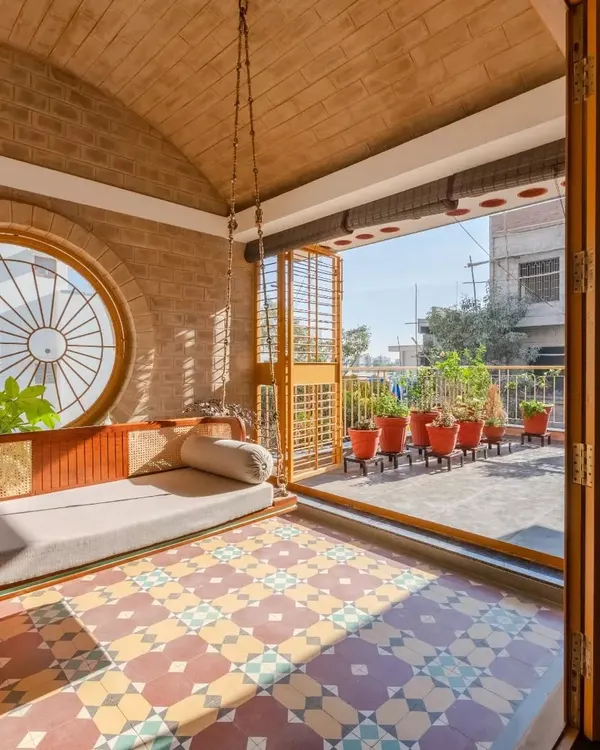 The semi-outdoor family space at Audumbara, featuring our custom-designed teak and rattan swing. The vaulted brick roof and patterned tiles create a captivating retreat.