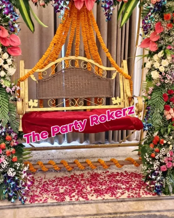 A beautifully decorated swing (jhula) for a Teej celebration, fully covered in an arch of fresh, exotic flowers like anthuriums, orchids, and roses, with traditional marigold garlands. This is our specialty for creating the perfect photo-worthy moment.