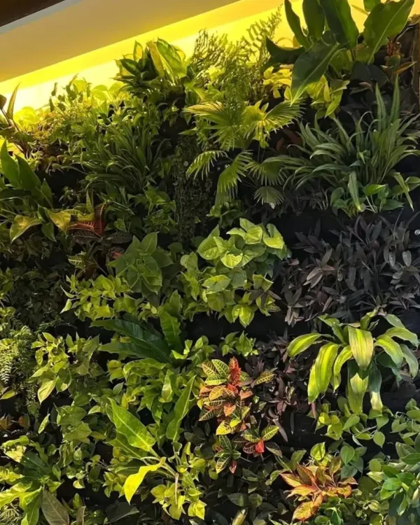 A detailed view of a dense, jungle-style artificial wall. The mix of ferns, broadleaf plants, and trailing vines creates a rich, textured, and hyper-realistic look.