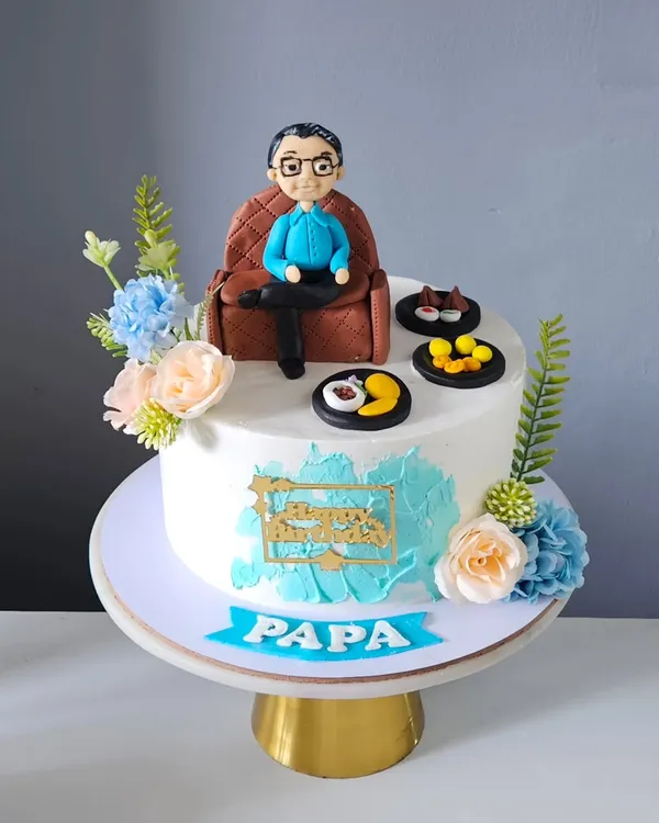 A full view of the personalized cake for "Papa," featuring his edible miniature relaxing on a custom-made fondant armchair. The entire scene, including the cake and toppers, was designed to celebrate him in a unique and heartfelt way.