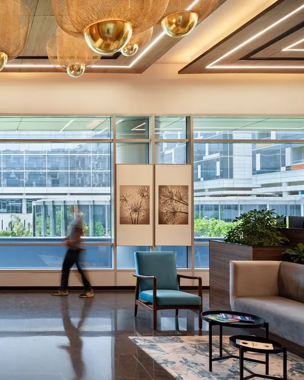 The lounge and reception area of the APT office in New Delhi, designed to be both sophisticated and inviting. The space uses warm wood tones, comfortable seating, and abundant natural light to create a positive first impression.