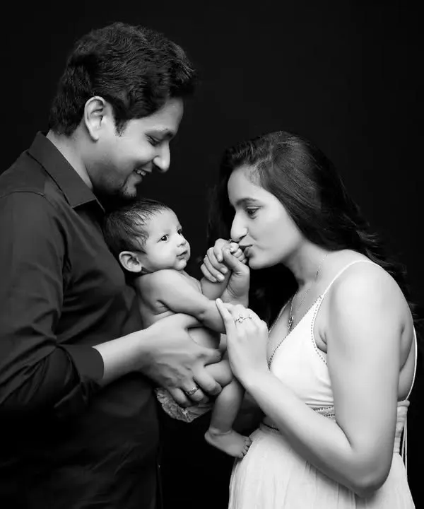 A timeless black and white studio portrait capturing the tender moment between new parents and their newborn baby. This classic style focuses on the emotional connection, creating an invaluable first family memory.