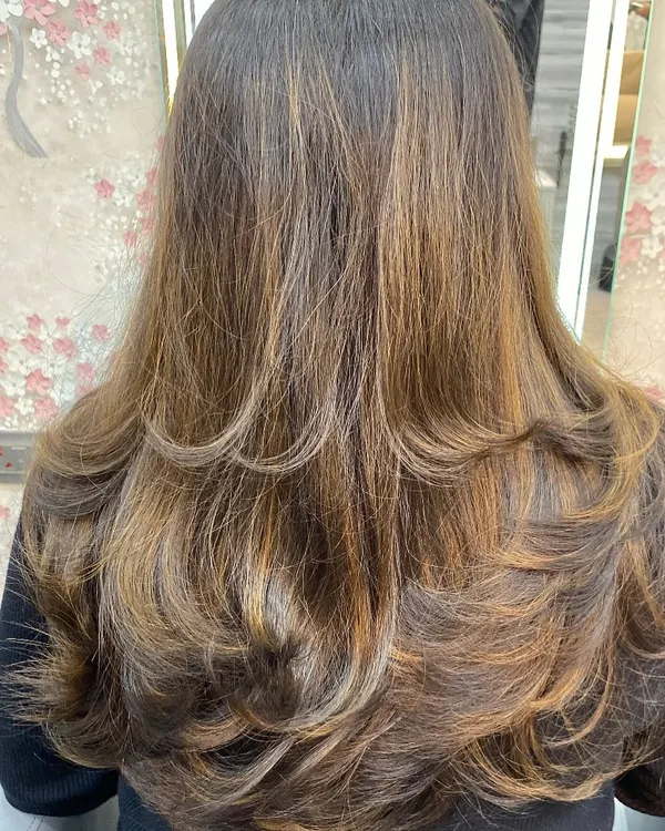 A layered haircut with subtle highlights, styled with an inward curl to create volume and shape.
