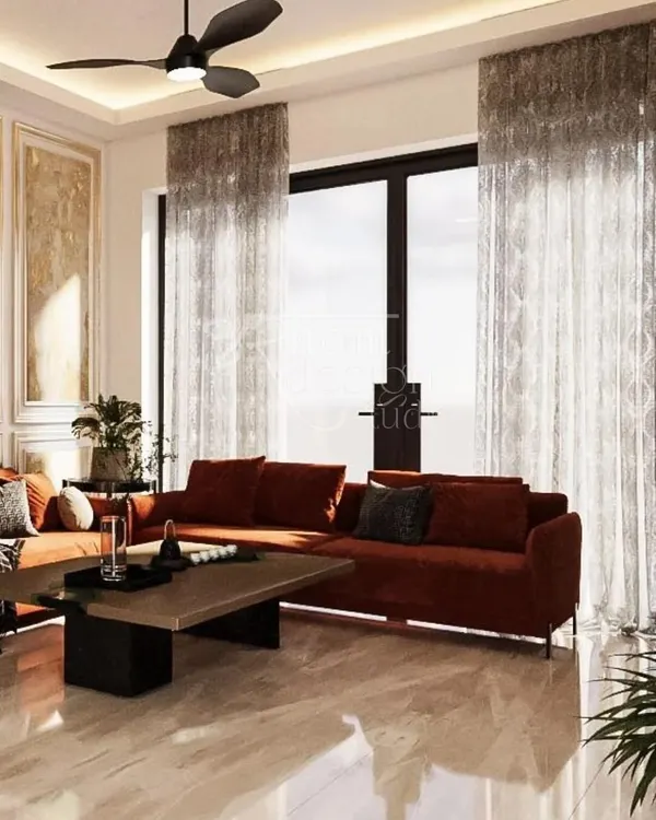 The main seating area of the Lajpat Nagar vacation home, designed to be bright and airy. The rust-colored sofa adds a pop of warmth against the neutral marble flooring and sheer curtains that filter the natural light beautifully.