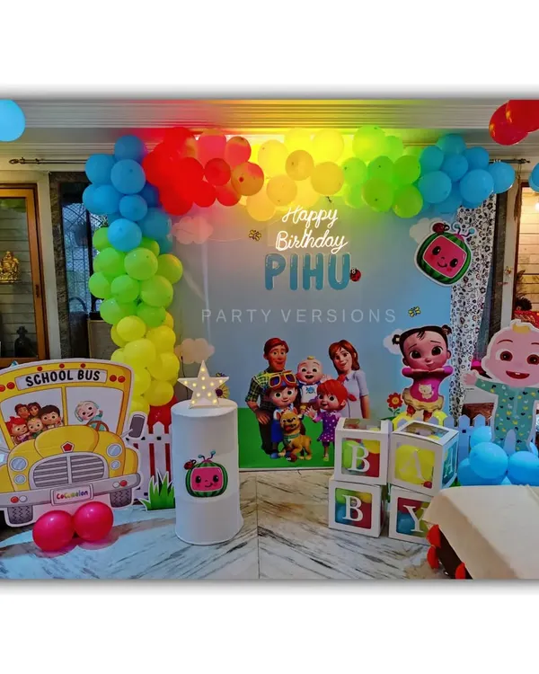 A complete Cocomelon birthday theme setup for Pihu's party at home. This includes a colorful backdrop, character cutouts, a balloon garland, and even a themed school bus prop.