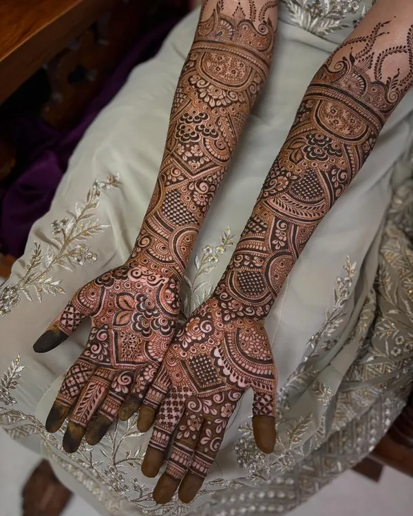 A complete view of a full bridal mehendi in the Pakistani style. Notice how the patterns flow from the fingertips all the way to the elbows, creating a seamless and intricate sleeve of henna.