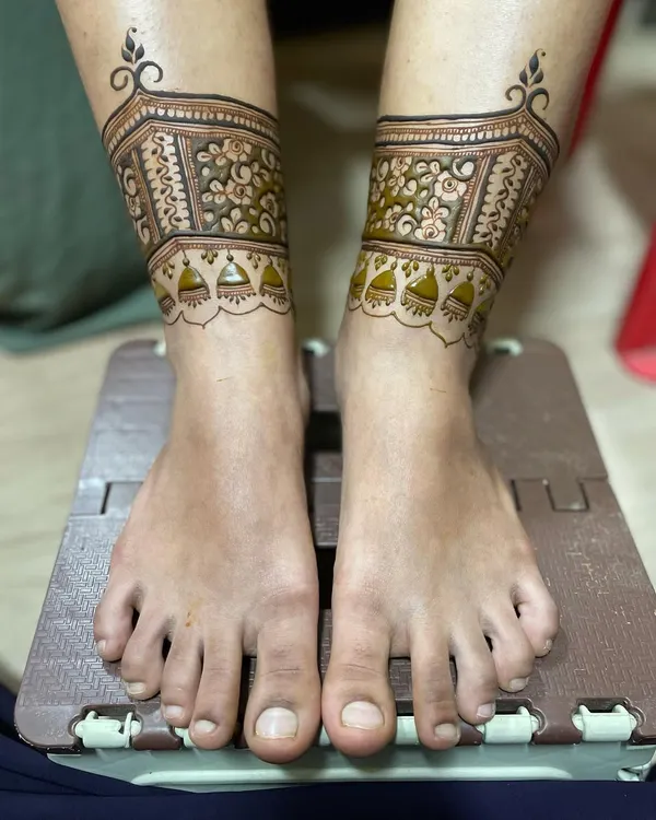 The first step of a bridal leg design. This shows the delicate floral band with hanging 'jhumki' or bell motifs.