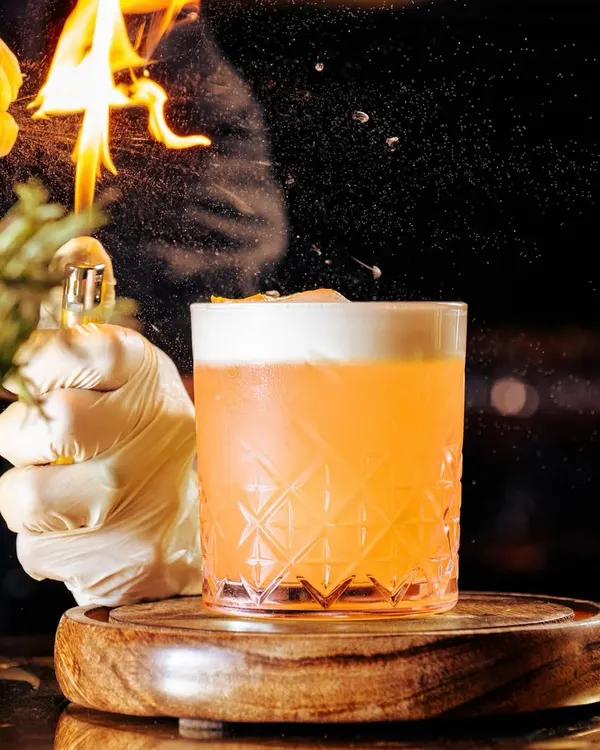 Great cocktails are about blending beautiful presentation and exquisite taste. Here, our mixologist adds a flaming citrus peel to a classic cocktail, creating a spectacle of flavor and aroma.