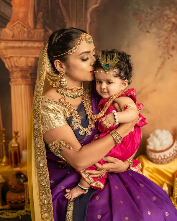 A mother's tender kiss for her little Krishna. This close-up shot is full of emotion, set against a rich, traditional backdrop that brings the Janmashtami theme to life.