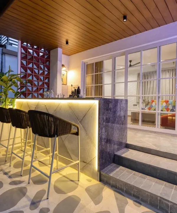 The rooftop bar at Villa 17, designed for breezy evenings. The counter features a geometric pattern with backlighting, complemented by Greek-inspired flooring and comfortable bar stools.