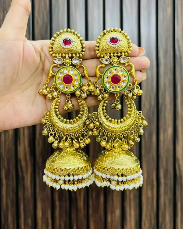 A stunning pair of gold-plated chandbali jhumkas with red and green meenakari work and pearl details. These are perfect for adding a touch of royalty to any ethnic outfit.