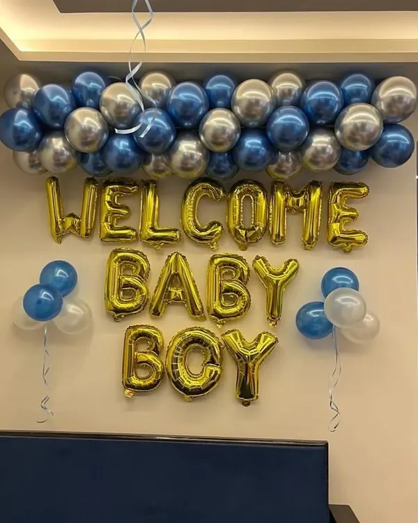 A classic and simple wall decoration to welcome a baby boy. This setup includes "WELCOME BABY BOY" foil balloons in gold, with a garland of chrome blue and silver balloons on top. It's a quick and affordable option.