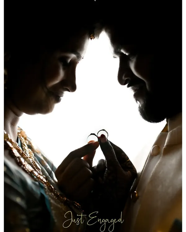 A silhouette of the couple holding their rings together against a bright background. This artistic shot creates a powerful and intimate image focused solely on their commitment.