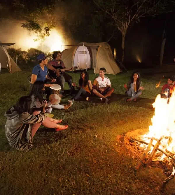 Gather 'round the campfire. A group of friends and family share music and stories by the fire, a perfect ending to an adventurous day.