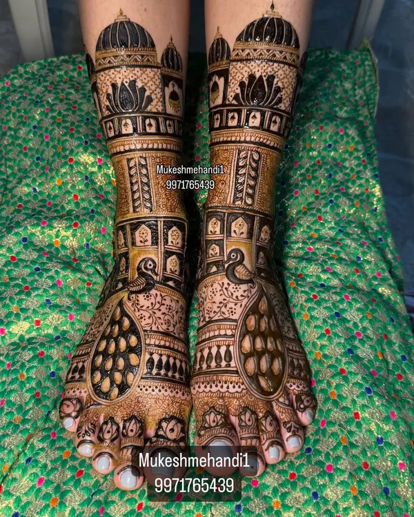 A stunning example of full bridal feet mehndi. This design features majestic peacocks and intricate architecture, creating a look of pure royalty.