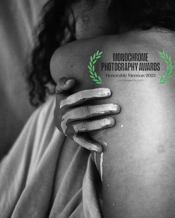 This award-winning monochrome photograph explores touch and texture. The image, which received an honorable mention at the Monochrome Photography Awards, focuses on the detail of a paint-covered hand on skin.