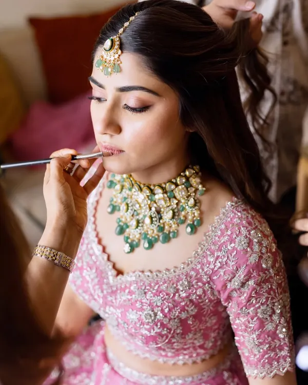 The final touches are just as important as the first. Here, I'm applying lipstick to complete this dreamy pink bridal look, ensuring the shade perfectly complements the outfit and skin tone.