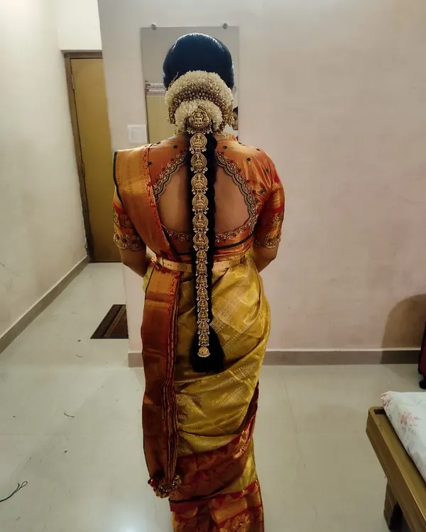 A stunning view of the complete traditional bridal hairstyle, adorned with our temple-style 'Jade Bangara' (hair braid ornament) and fresh flowers. This is the perfect finishing touch for a South Indian bride.