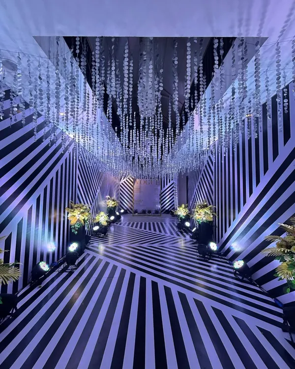 We created this mesmerizing entrance tunnel for a Sangeet night using a bold black-and-white striped pattern. The geometric design and cascading crystal strings make for a dramatic and high-fashion statement.