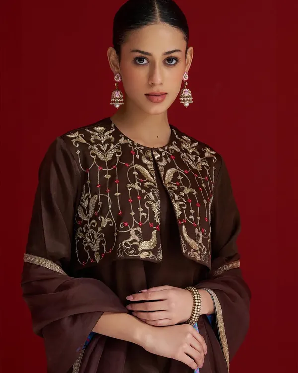 A rich brown suit with a beautifully embroidered jacket. The intricate bird and floral motifs in gold thread add a touch of whimsical elegance to this classic silhouette.