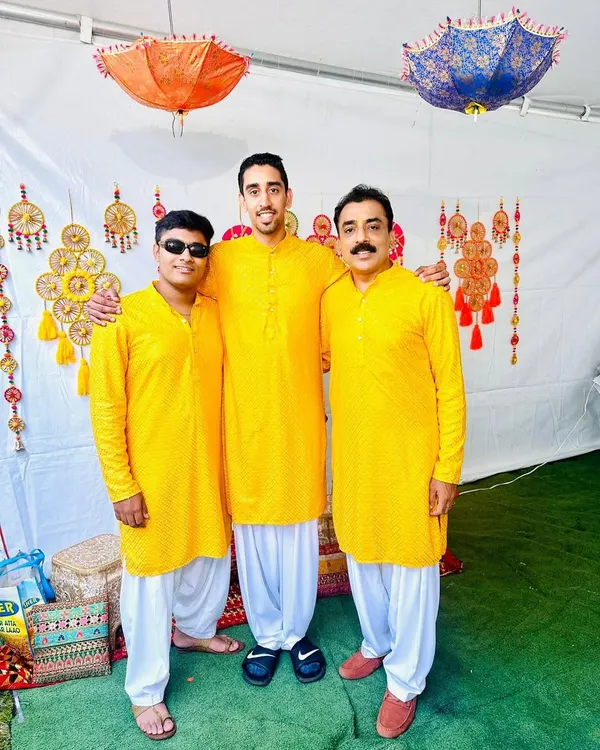 A happy family in matching bright yellow kurta sets for a Haldi function. We can create coordinated looks for the entire family to celebrate special moments together.