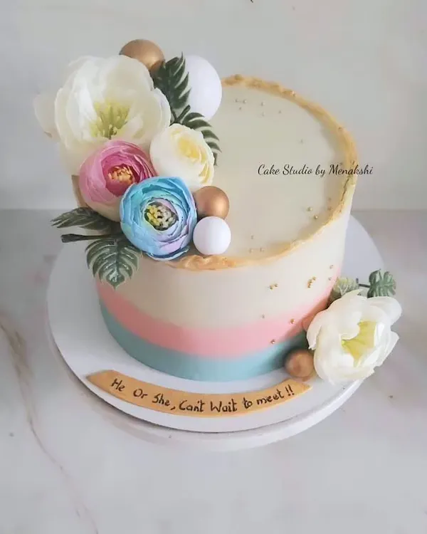 A lovely floral baby shower cake with soft hues of pink and blue. The message "He or She, Can't Wait to Meet You" makes it perfect for a gender reveal party.