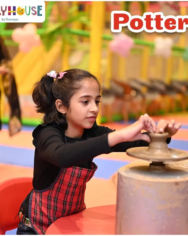 A close-up of a young girl trying her hand at the pottery wheel. Our instructors provide guidance, helping children shape their own clay creations from start to finish.