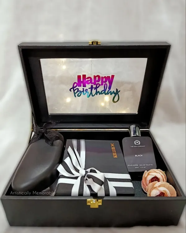 An open view of a classic men's birthday hamper. This one features a light-up lid, a sleek wallet, perfume, and other accessories, all nestled in a reusable suede box.