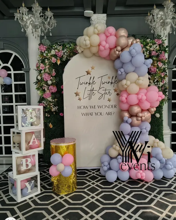 An elegant baby shower setup with a "Twinkle Twinkle Little Star" theme. It features a pastel balloon arch, "BABY" blocks, and a custom backdrop for a gender reveal party.
